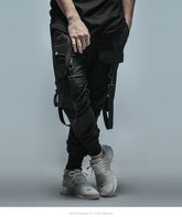 Black cargo fitness pant men with multiple pockets and straps, paired with light gray sneakers