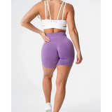 Purple Nvgtn Seamless Pro spandex shorts with white sports bra