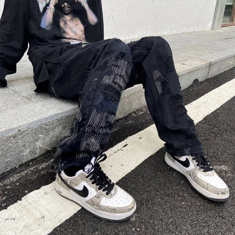 Distressed black jeans with rips and patches paired with Nike sneakers by 7TT Original National