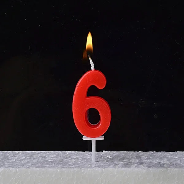 Lit red number 6 birthday candle atop a Champagne Gold Paraffin Candle