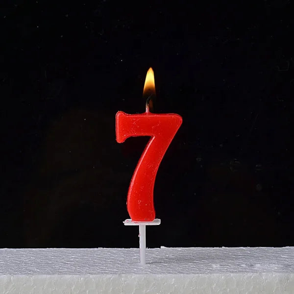 Lit red number 7 birthday candle atop a Champagne Gold Paraffin Candle showcasing elegance