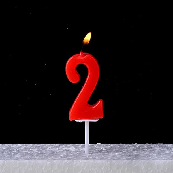 Red number 2 birthday candle flame on Champagne Gold Paraffin Candle display