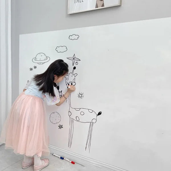 Person in a pink tulle skirt creating giraffe art on a wall with a whiteboard sticker