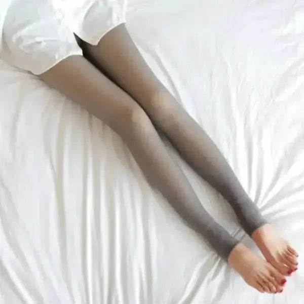 Women’s fleece lined thermal stockings on gray leggings over white bedding