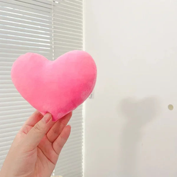 Pink plush heart held by a hand, perfect for Valentine’s Day as a seat cushion