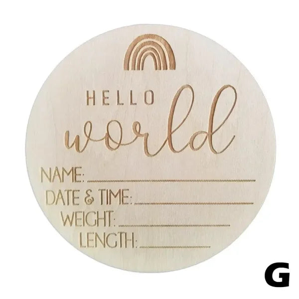 Wooden birth announcement disc with Hello World text and baby details on natural wood chips