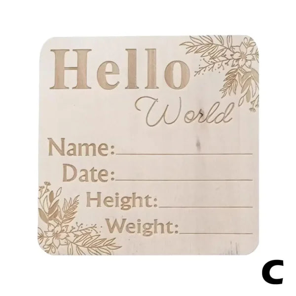 Birth announcement milestone board with Hello World text on natural wood chips