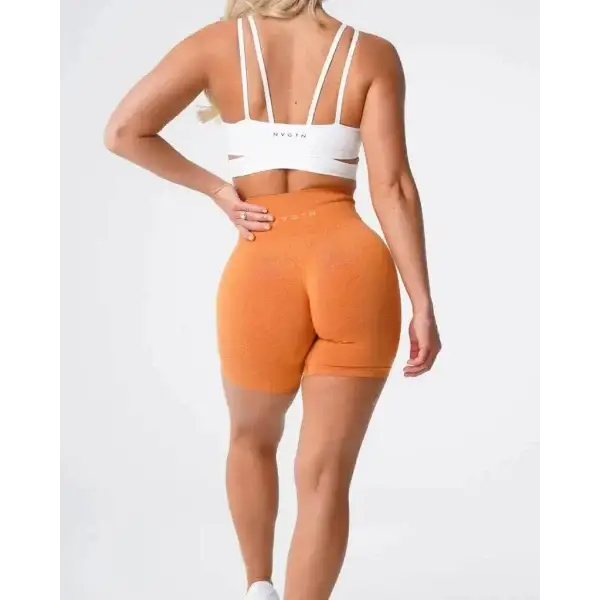 Nvgtn Seamless Pro spandex shorts in orange with white sports bra