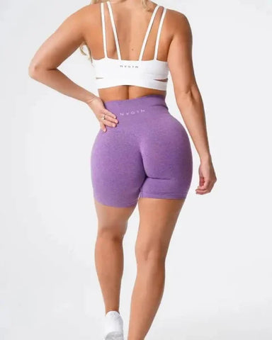 Purple high-waisted Nvgtn Seamless Pro Spandex Shorts paired with a white sports bra
